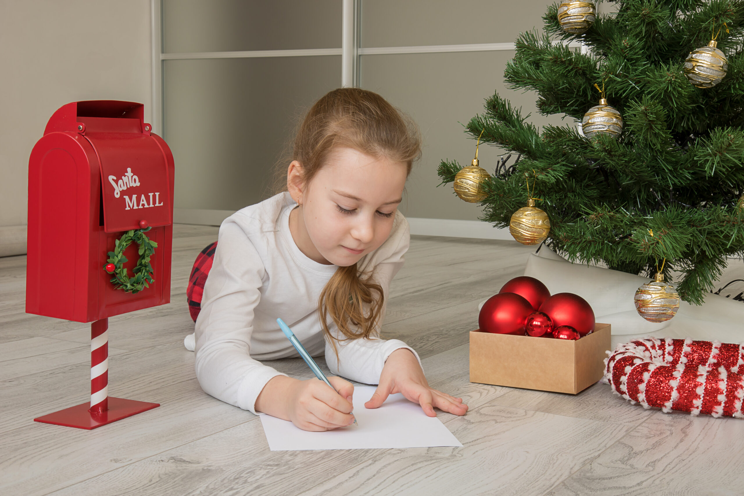 girl in pajamas writes a letter to Santa near the Christmas tree, Christmas, Christmas gifts.